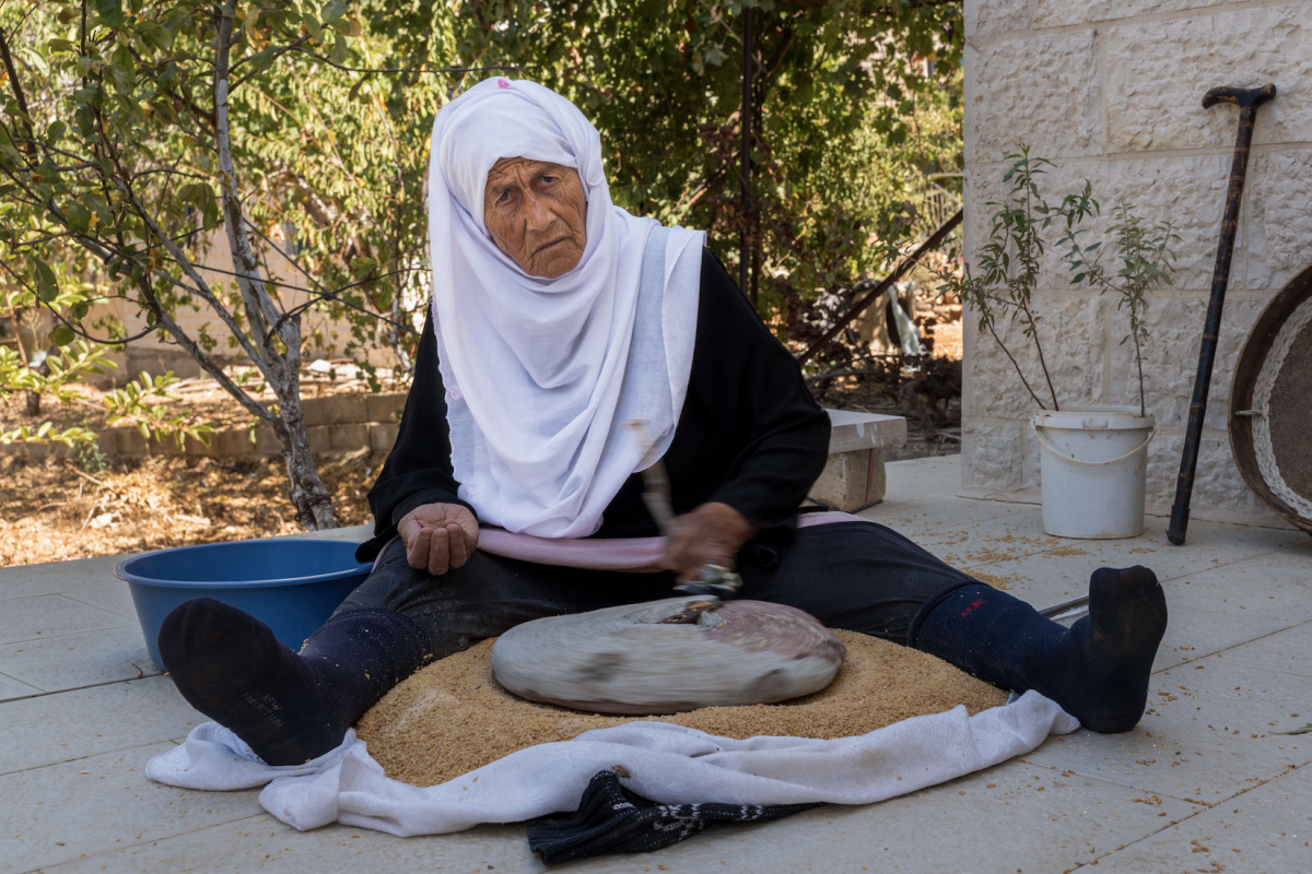 elderly Palestinian woman cooks outside