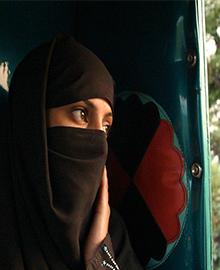 woman in burqa looking out a window