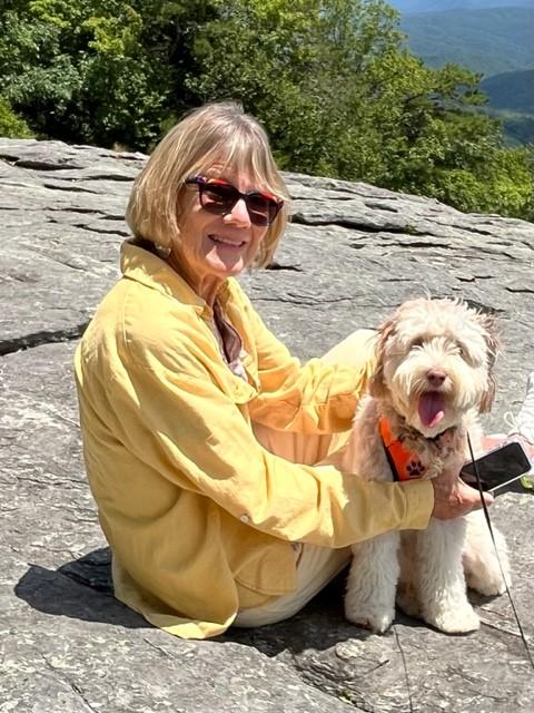 photo of Meg Eggleston on mountain sitting next to a small dog