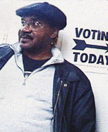 black man standing in front of a "Voting Today" sign